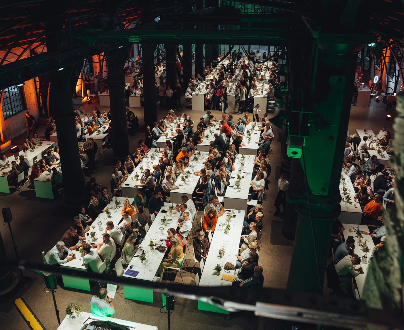 Blick von oben in eine Halle mit vielen geschmückten Tischreihen und zahlreichen LTS-Mitarbeitenden; über dem Bild liegt der Text ‚Unternehmensfest‘.