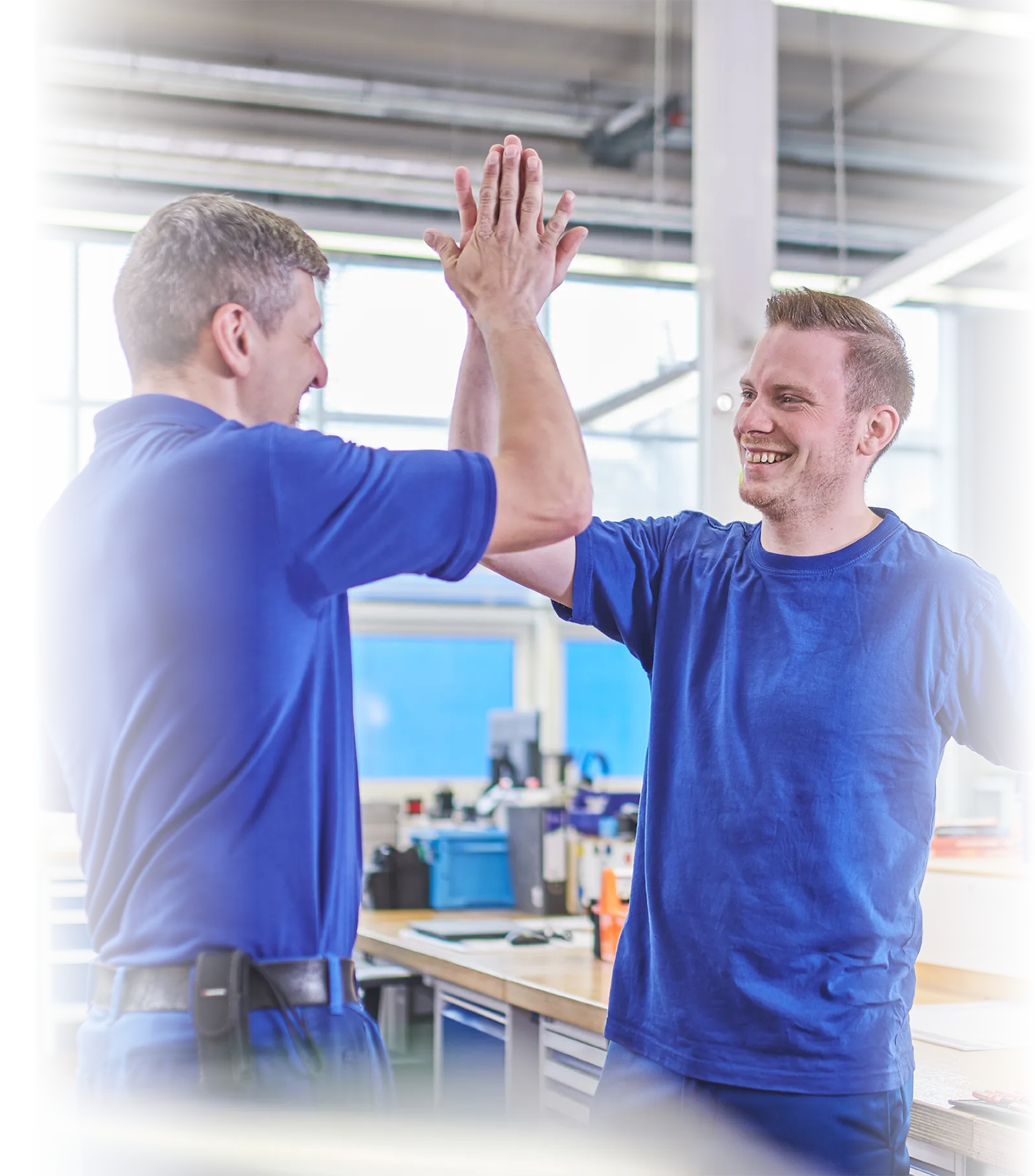 Zwei LTS-Mitarbeiter in blauen T-Shirts geben sich im LTS-Lager High-Five.
